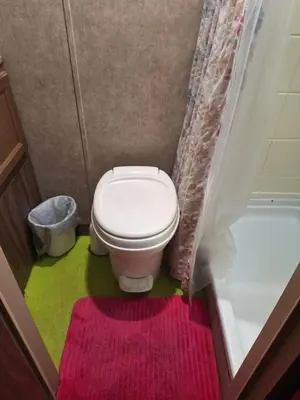 a bathroom with a toilet with a pink and green rug at Tiny Trailer happy hole in the wall in Orlando