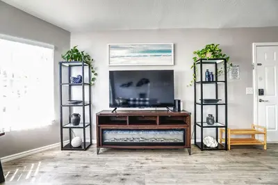 a living room with a flat screen tv on a entertainment center at 3BD Townhome with Pool 12mi to Disney and Universal in Kissimmee