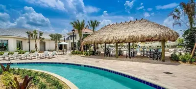 a resort swimming pool with chairs and a straw umbrella at Go08 - STOREY LAKE in Kissimmee