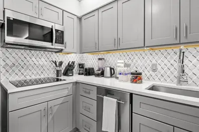 a kitchen with white cabinets and a sink and a microwave at 1BR Suite Prime Orlando Location in Orlando