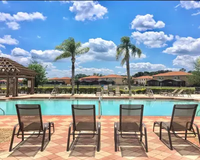 a group of chairs sitting in front of a swimming pool at Resort 4 Br 3 Ba Private Pool Home & Lake View near Disney & Universal in Kissimmee