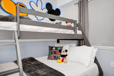 a bedroom with bunk beds with a mickey mouse pillow at 2BR Family Condo Near Disney, Universal and More in Kissimmee