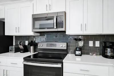 a kitchen with white cabinets and a stove and a microwave at 2BR Family Condo Near Disney, Universal and More in Kissimmee