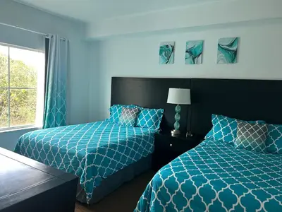a blue bedroom with two beds and a window at Cozy Condo near Disney World with Shuttle to parks in Orlando