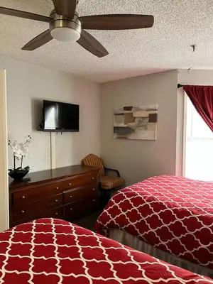 a bedroom with a red bed and a ceiling fan at Condo near Disney Universal Free Parking in Orlando