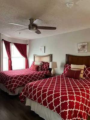 a bedroom with a red bed and a ceiling fan at Condo near Disney Universal Free Parking in Orlando