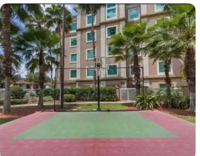 a basketball court in front of a building with palm trees at Renovated Condo near Disney Free Shuttle to Parks in Orlando