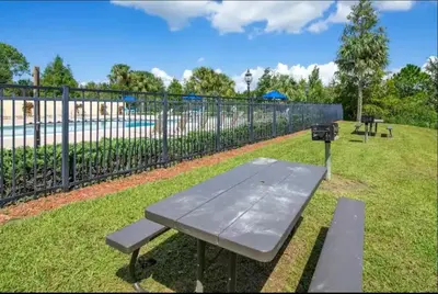 a picnic table in a park next to a fence at Amazing Condo near Disney in Kissimmee