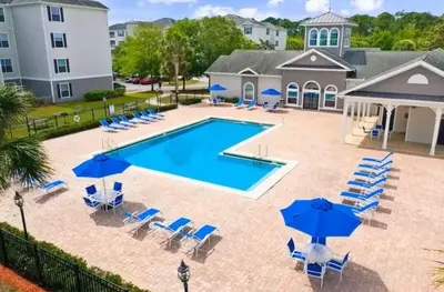 an image of a swimming pool with chairs and umbrellas at Amazing Condo near Disney in Kissimmee