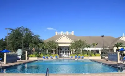a pool at a resort with chairs and a building at Renovated 4 bed3 bath Townhome near Disney in Kissimmee