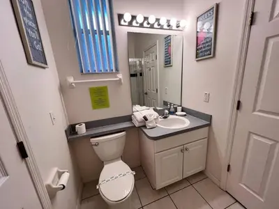 a bathroom with a toilet and a sink and a mirror at Villa near Disney Jacuzzi Pool 4bed-3baths in Kissimmee