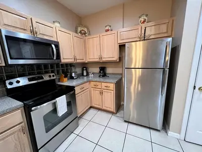 a kitchen with wooden cabinets and a stainless steel refrigerator at Villa near Disney Jacuzzi Pool 4bed-3baths in Kissimmee