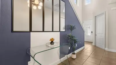 a hallway with a glass table and a blue wall at Upstay Spacious 5BR Villa Private Pool and Hot Tub in Orlando