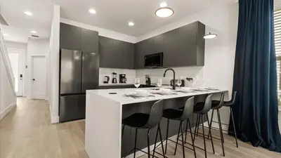 a kitchen with a white island with black bar stools at Contemporary 4BR Townhome with Pool & Themed Rooms in Orlando