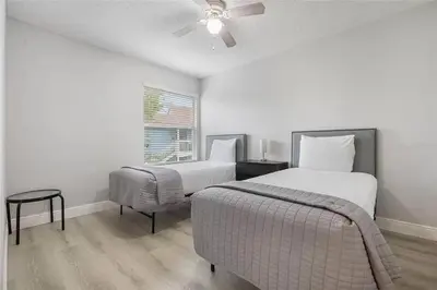 a bedroom with two beds and a chair and a ceiling fan at 3BR Condo Near Disney, with Clubhouse, Pool and Gym in Kissimmee