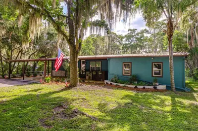 a blue house with an american flag in front of it at Lakefront Home with Hot Tub and Dock in Orlando! in Orlando