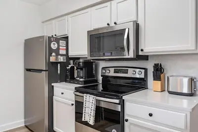 a kitchen with white cabinets and a stove and a microwave at Magical 3BR Luxury Condo - 15 Mins to Disney in Kissimmee