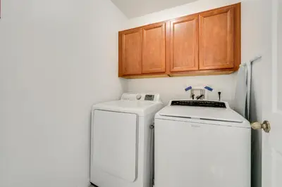 a small kitchen with a white refrigerator and wooden cabinets at Kissimmee Resort-Style Home Close to Shops and Eats in Kissimmee