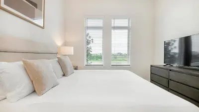 a white bedroom with a large bed and a television at Landing Incredible 1BD Gym Clubhouse in Orlando