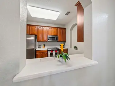 a kitchen with wooden cabinets and a vase of flowers on a counter at Magnificent 2 Bedroom Apt Vista Cay Resort 107 in Orlando