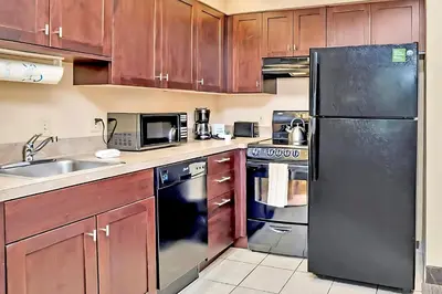 a kitchen with wooden cabinets and a black refrigerator at King Suite near to Disney & Universal Fun in Orlando