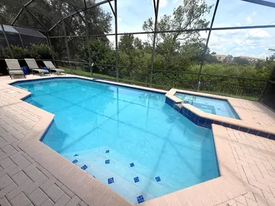 a large blue swimming pool with chairs and trees at The Windsor Hideaway in Orlando