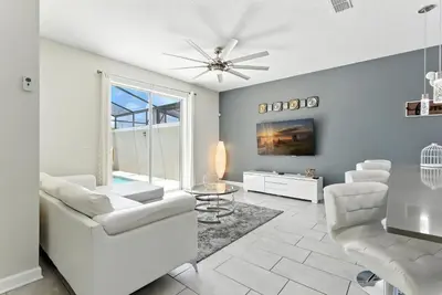 a living room with white furniture and a ceiling fan at Comfort Stay with Pool Near Attractions in Kissimmee