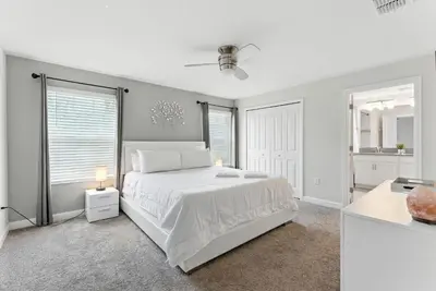a white bedroom with a white bed and a window at Comfort Stay with Pool Near Attractions in Kissimmee