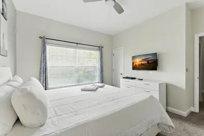 a white bedroom with a large bed and a window at Comfort Stay with Pool Near Attractions in Kissimmee