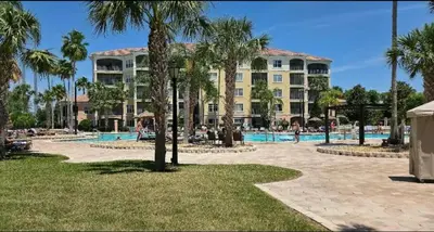 a resort with a pool and palm trees and a building at Worldquest Resort Luxurious Pet Friendly Condo in Orlando