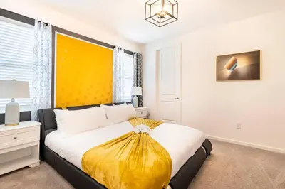 a bedroom with a large bed with a yellow headboard at Sleeps 36 | 15 Bedroom! Theater! Resort! POOL! in Kissimmee