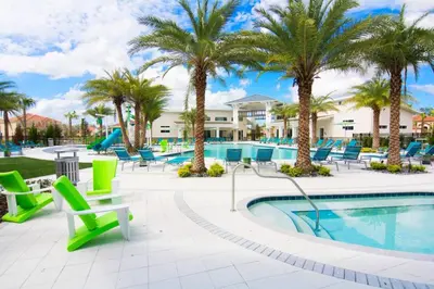 a pool with chairs and palm trees at a resort at Sleeps 36 | 15 Bedroom! Theater! Resort! POOL! in Kissimmee