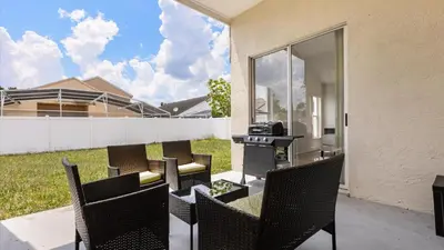 a patio with chairs and a grill in a backyard at Upstay 3BR Family-Friendly Stylish Retreat w Patio in Kissimmee
