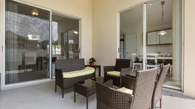 a patio with wicker chairs and a table and a dining area at Upstay 3BR Family-Friendly Stylish Retreat w Patio in Kissimmee