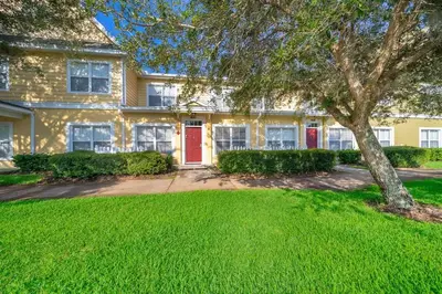 a yellow house with a red door and a tree at Charming 3BrTownhome near Disney in Kissimmee
