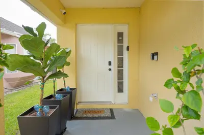 a front door of a house with two potted plants at Casa térrea c/ piscina e 2 suítes, sem carpete in Kissimmee