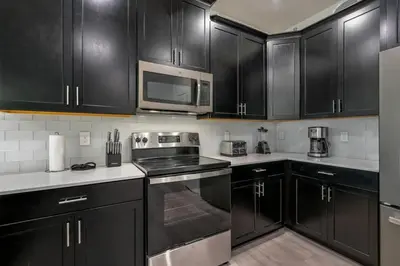 a kitchen with black cabinets and stainless steel appliances at villa 9 quartos com temas, pertinho da Disney! in Kissimmee