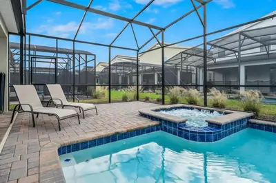 a patio with a swimming pool and two chairs and a building at villa 9 quartos com temas, pertinho da Disney! in Kissimmee
