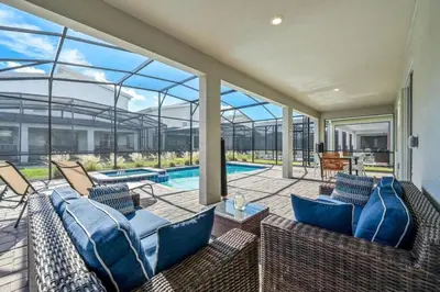 an indoor patio with blue furniture and a swimming pool at villa 9 quartos com temas, pertinho da Disney! in Kissimmee