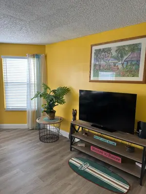 a living room with a flat screen tv and a table at Bright Condo near Disney and Universal in Kissimmee