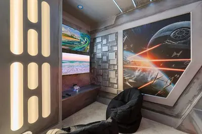 a person sitting in a chair in a room with a tv at Epic Disney Themehouse in Windsor (ADA option) in Orlando