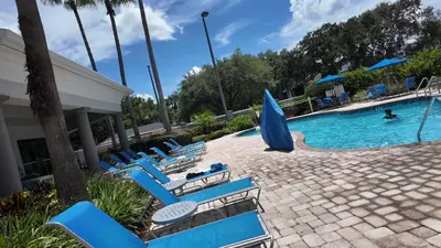 a pool with blue chairs and a person swimming in it at 110 - Next to Disney - Pool in Orlando