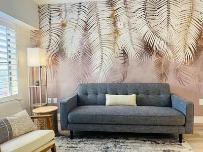 a blue couch in a living room with a palm tree mural at Condo near Epic & Universal,free parking & Netflix in Orlando