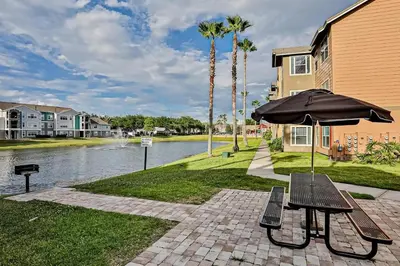 a picnic table with an umbrella next to a lake at Villa Velera in Kissimmee