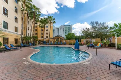 a pool with chairs and umbrellas in a courtyard at Harry Potter Stay Near Universal in Orlando