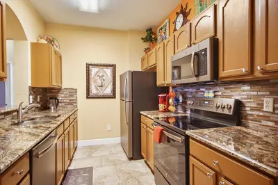 a large kitchen with stainless steel appliances and wooden cabinets at Palm Tree Paradise 3 bedroom condo at Windsor Hills close to Disney in Orlando