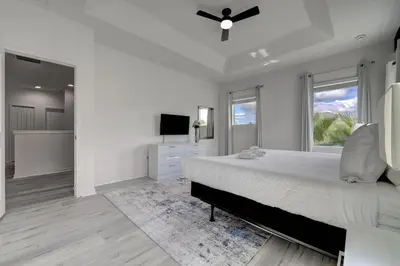 a white bedroom with a large bed and a television at Bellavida Resort Retreat with Private Pool in Kissimmee