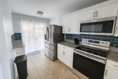 a kitchen with white cabinets and a stove and a microwave at Villa Central com Piscina perto da Disney in Kissimmee