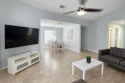 a living room with a couch and a tv and a table at Villa Central com Piscina perto da Disney in Kissimmee