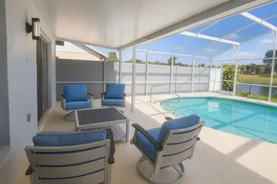 a balcony with a pool and chairs and a table and a tablektop at Villa Central com Piscina perto da Disney in Kissimmee